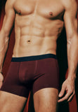 Man wearing maroon underwear against a dark background