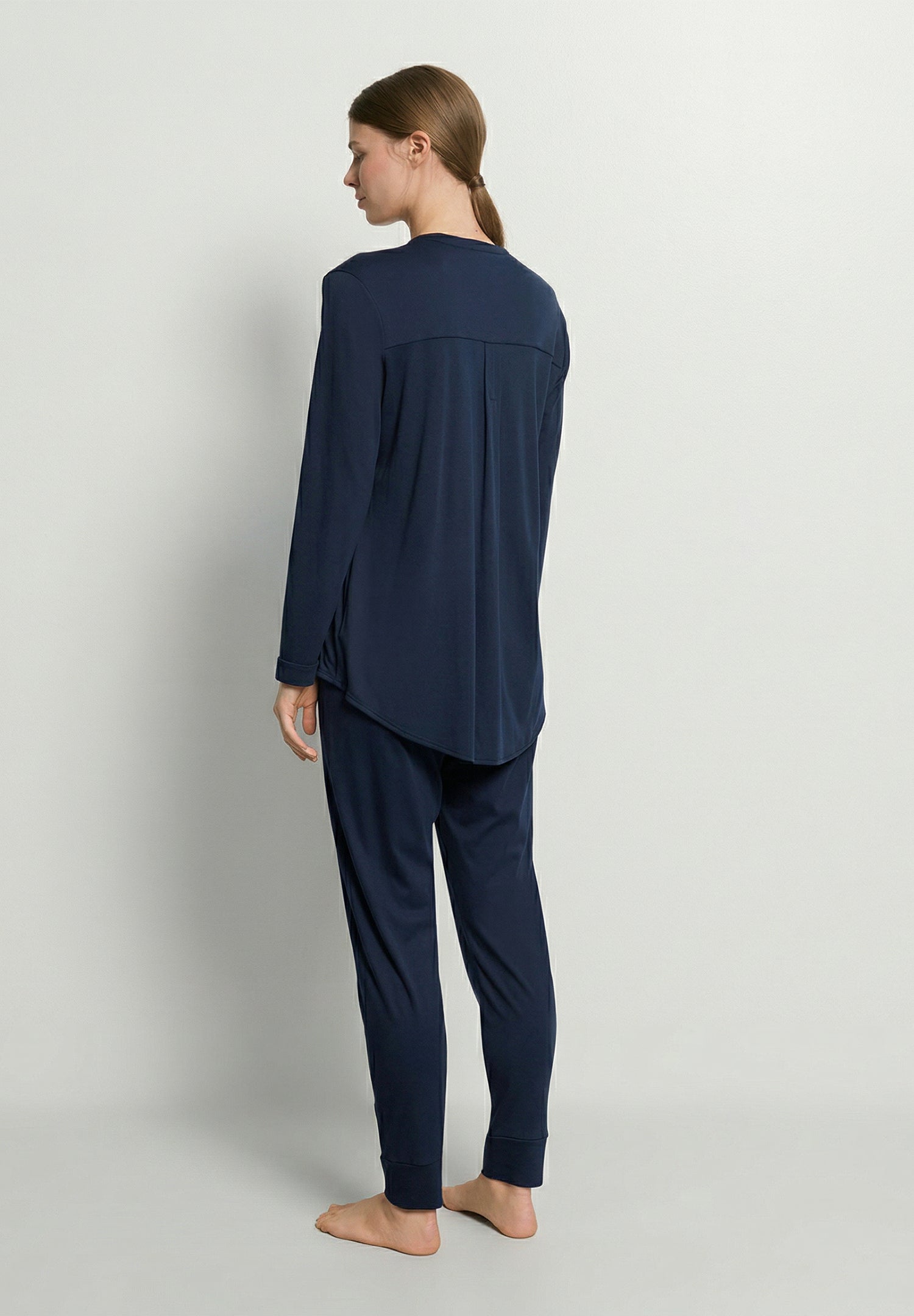 Person wearing a navy blue pajama set on a light gray background