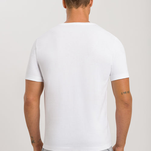 Man wearing a plain white t-shirt and gray pants on a light gray background