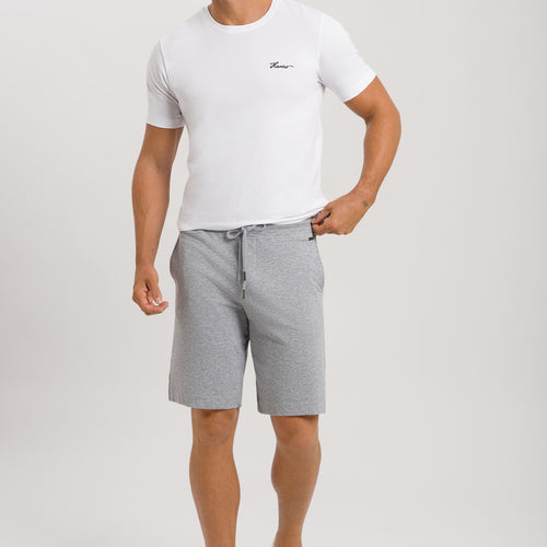Man wearing a white t-shirt and gray shorts on a plain background