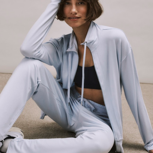 Woman in light blue Balance tracksuit sitting on the floor