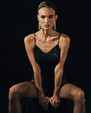 Woman in a black top with crystals sitting on a dark background