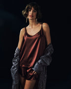 Woman wearing Grand Central Silk Camisole and Knickers in vivid brown with men's Selection robe falling off the shoulders