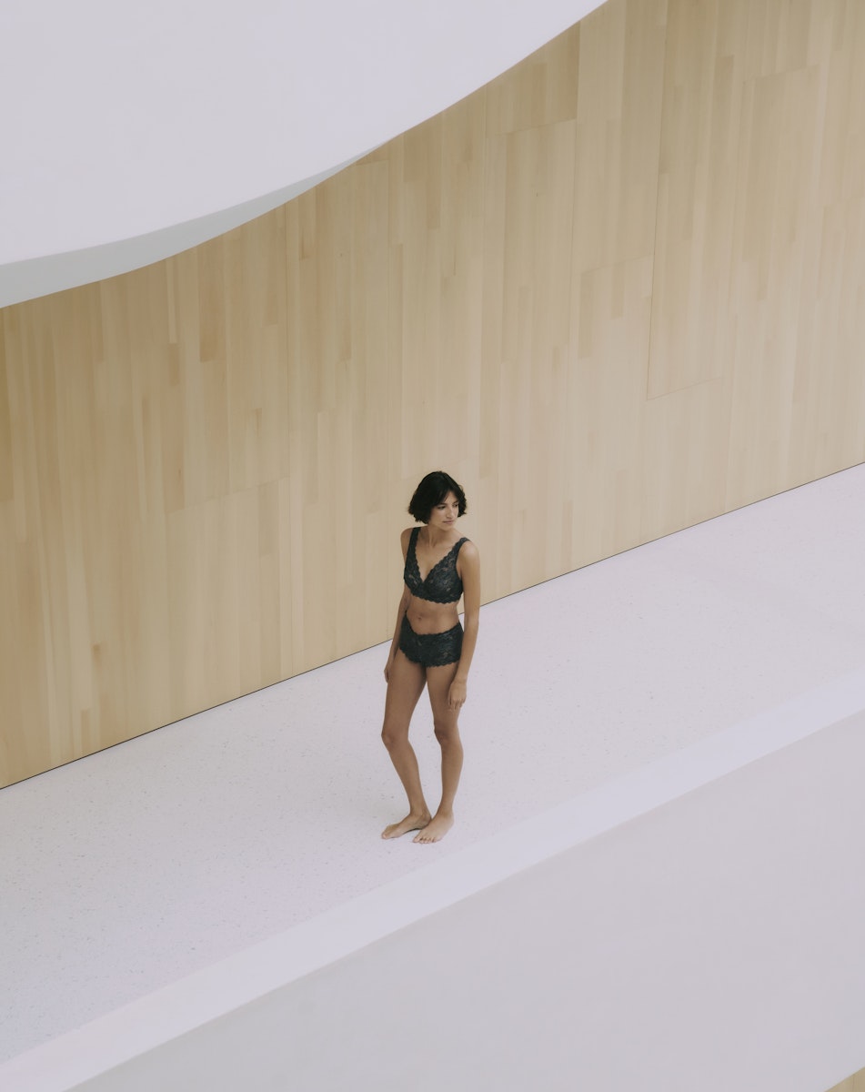 Woman wearing Luxury Moments standing in a minimalistic room with wooden walls and a white floor.