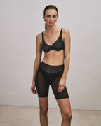 Woman wearing a black Smooth Illusion bra and shorts against a plain background