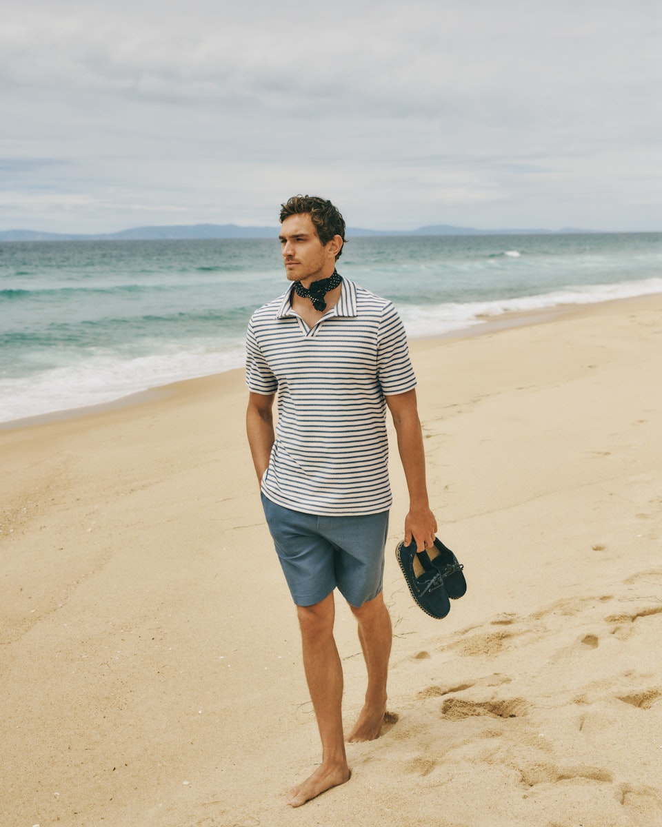 Man walking on beach with shoes in his hand