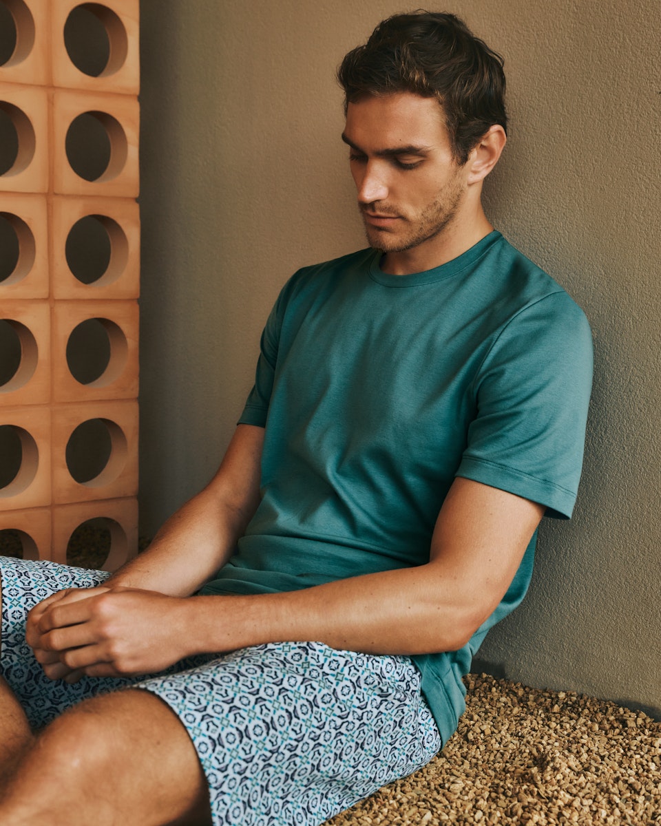 Man sitting against a wall wearing Night and Day Short Sleeve Pajama Set 