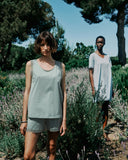 Two women standing in a lavender field with trees in the background