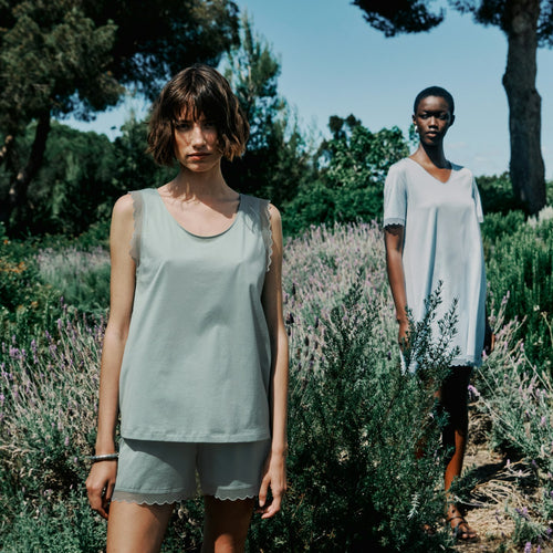 Two women standing in a lavender field with trees in the background
