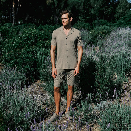 Man standing in a lavender field wearing a brown outfit.