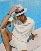 Person wearing a white outfit and hat by a pool