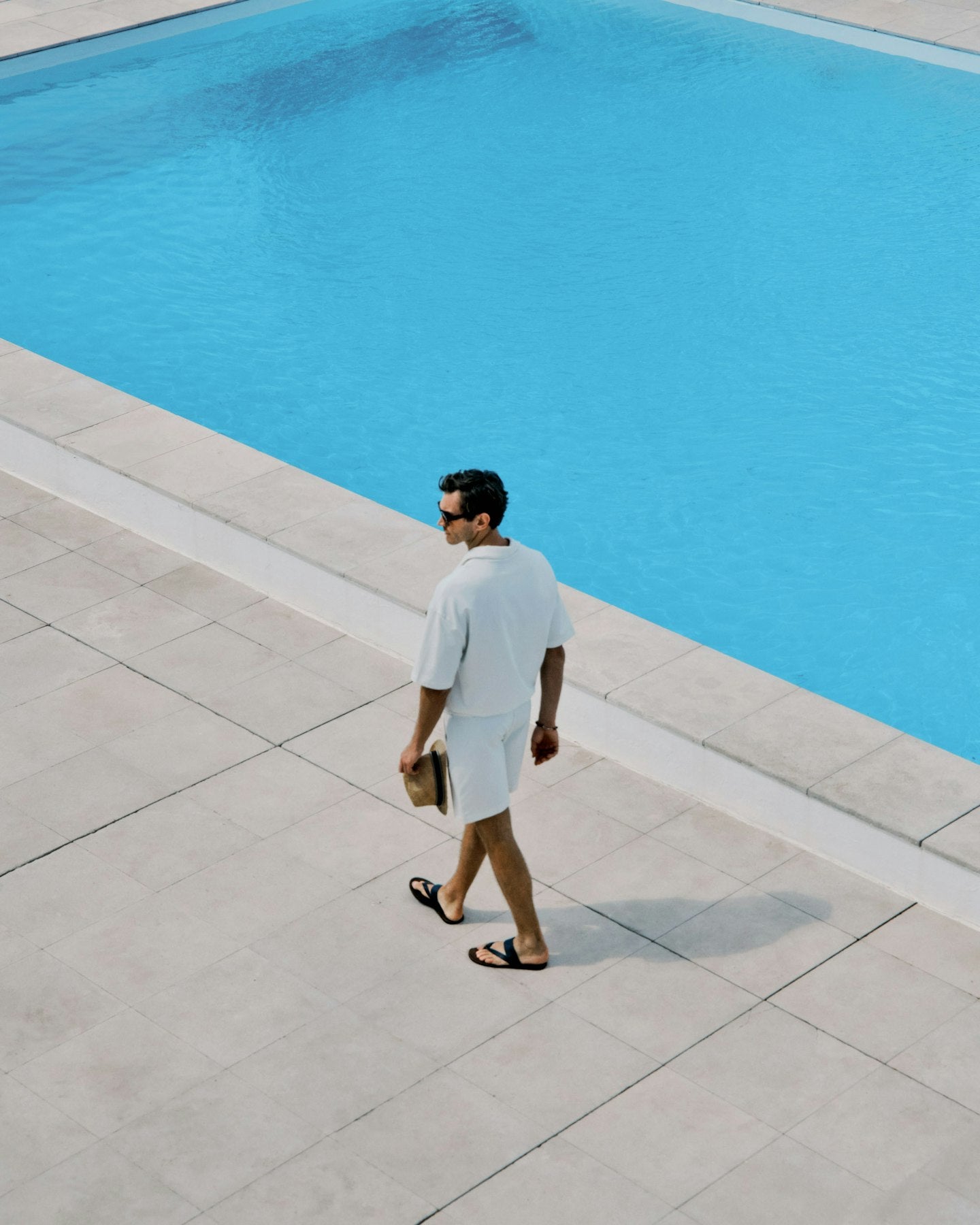 Man walking by a pool with clear blue water