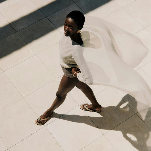 Woman walking on a tiled floor casting a shadow