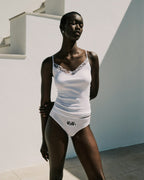 Woman wearing a white swimsuit with lace details against a light background