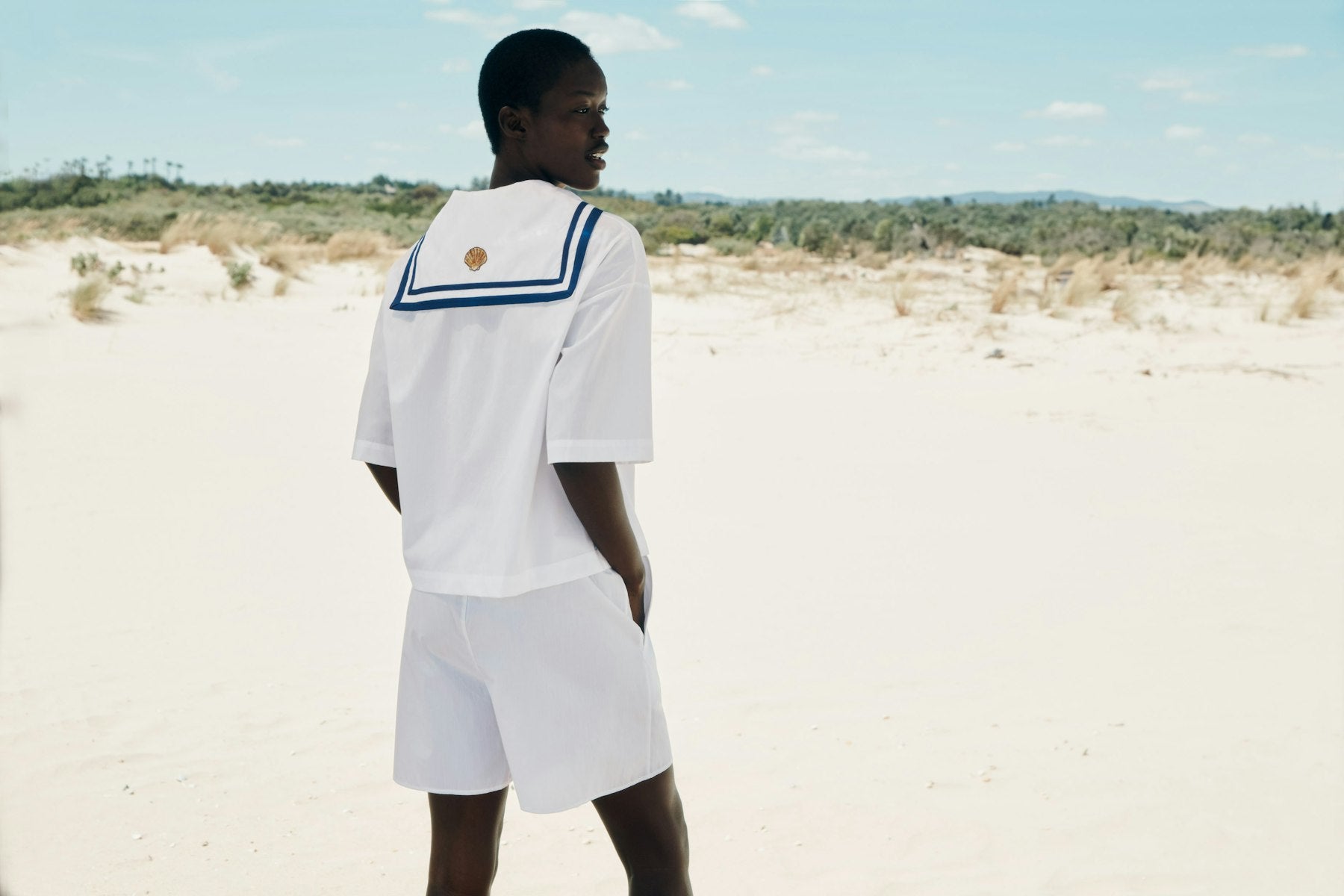 Person wearing a white outfit with a blue trim on the beach