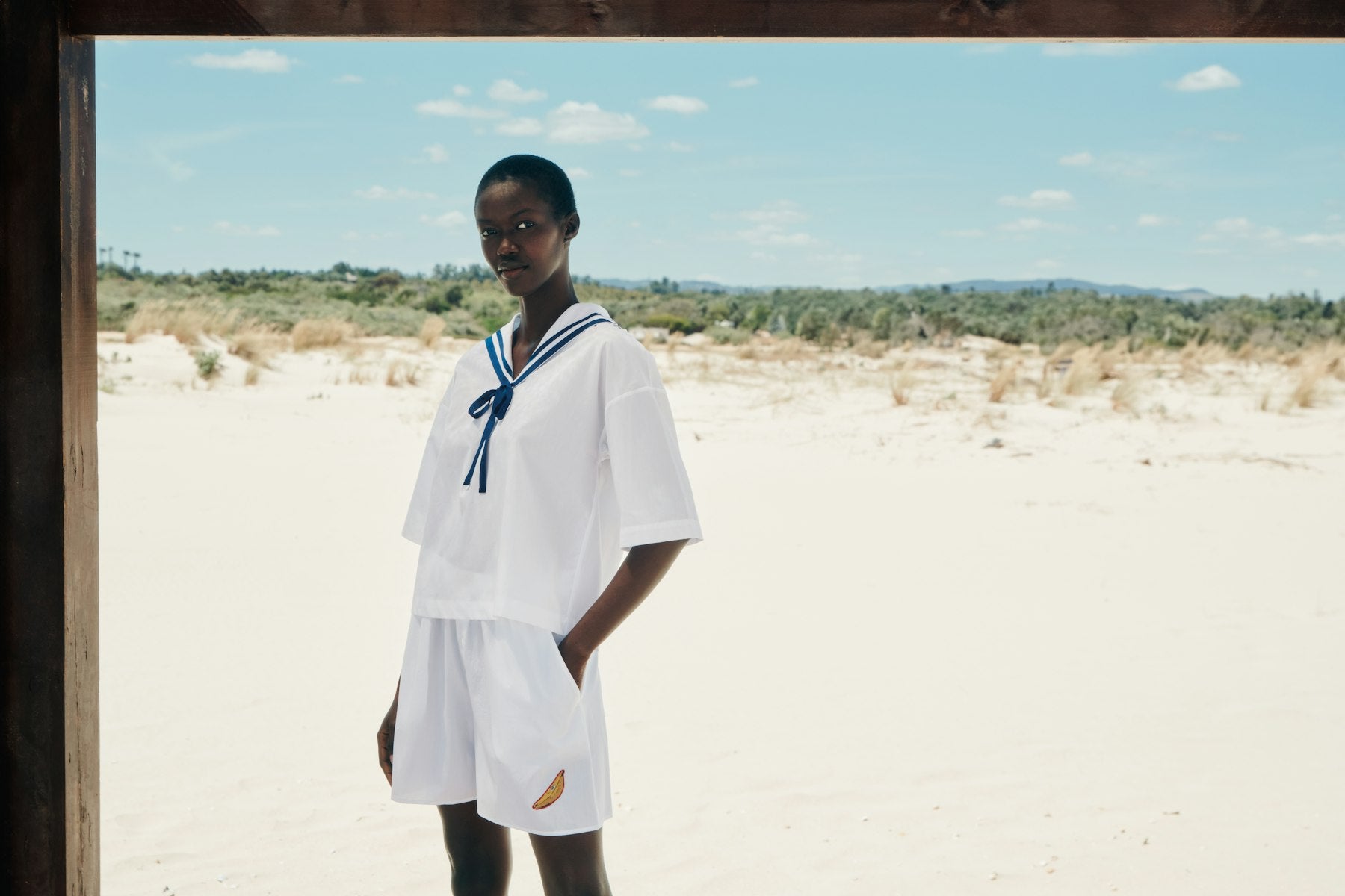 Woman wearing a white outfit and sailor shirt with a blue ribbon on the beach