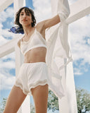 Woman in a white outfit standing outdoors with a clear sky background