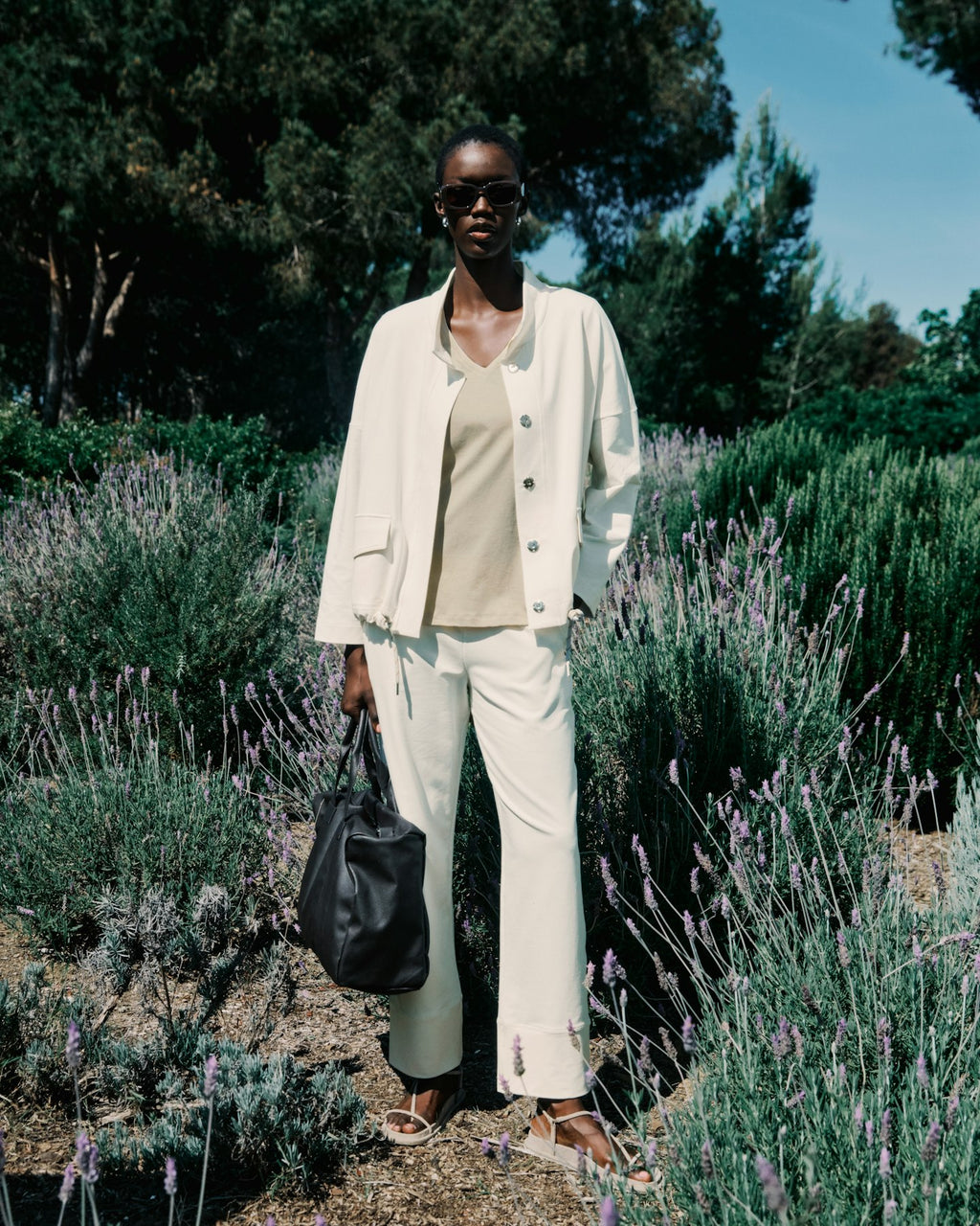 Person in a white outfit standing among lavender plants