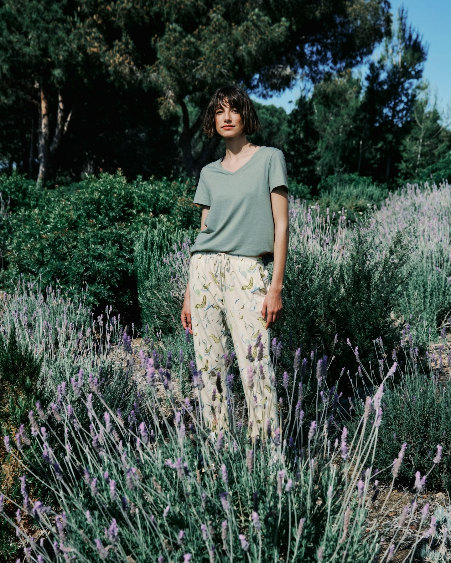 Woman standing in a field of lavender with trees in the background