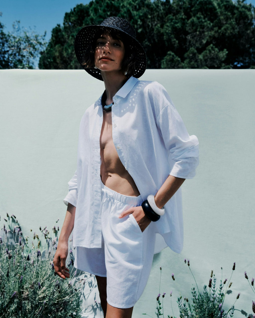 Woman in a white shirt and shorts standing outdoors with a blurred background