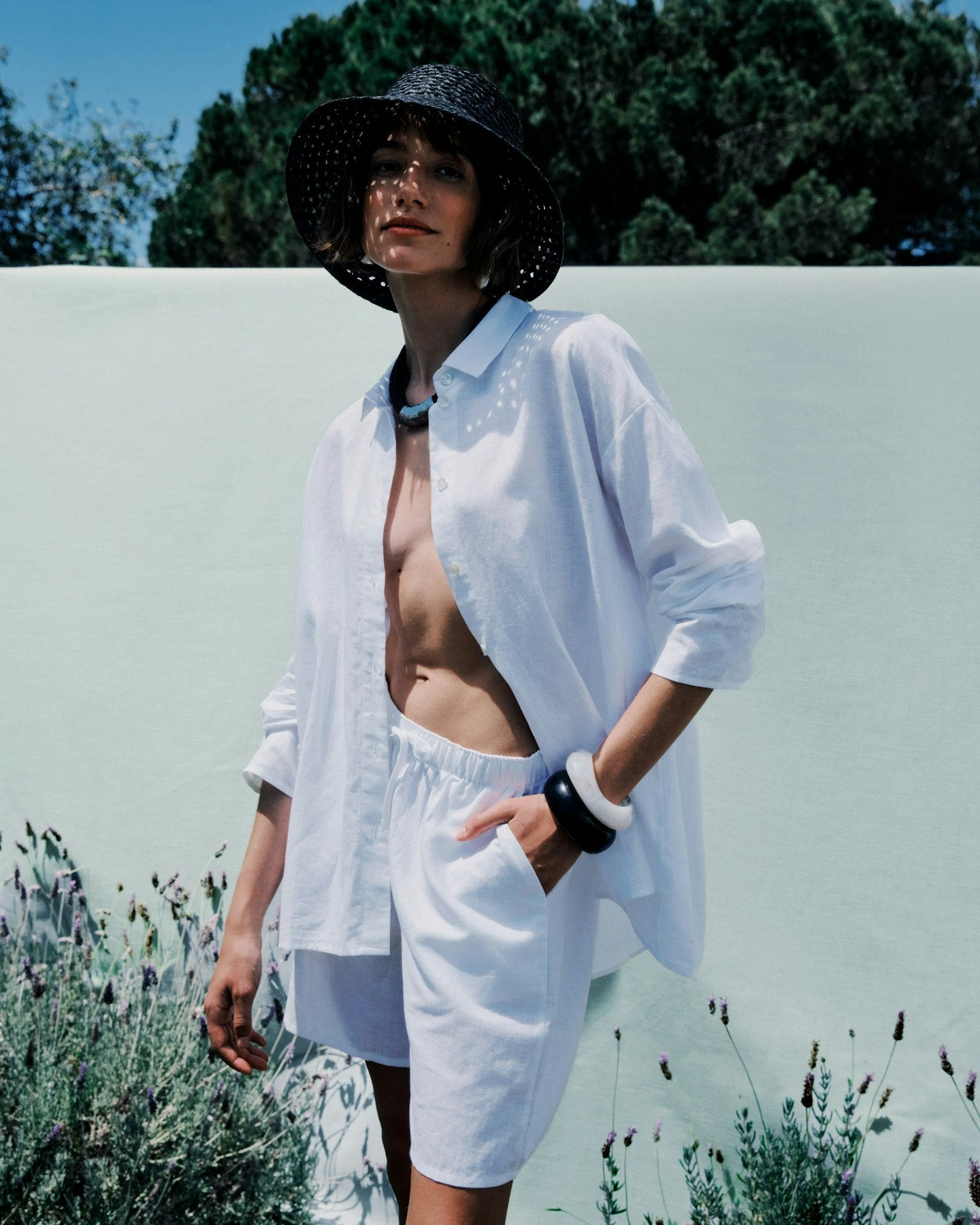 Woman in a white shirt and shorts standing outdoors with a blurred background
