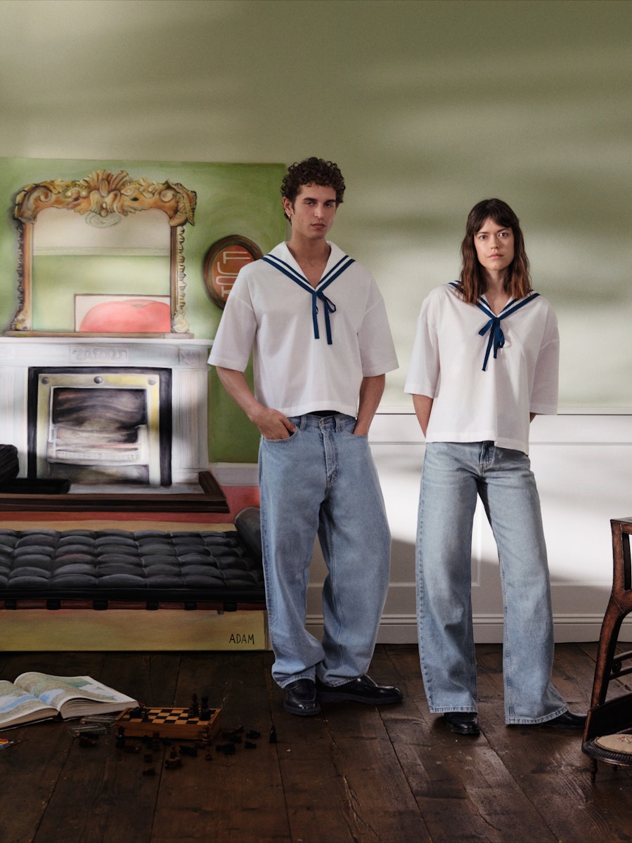 Two people wearing matching outfits in a room with a fireplace and mirror.