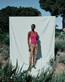 Woman standing in front of a white curtain outdoors with trees and plants around