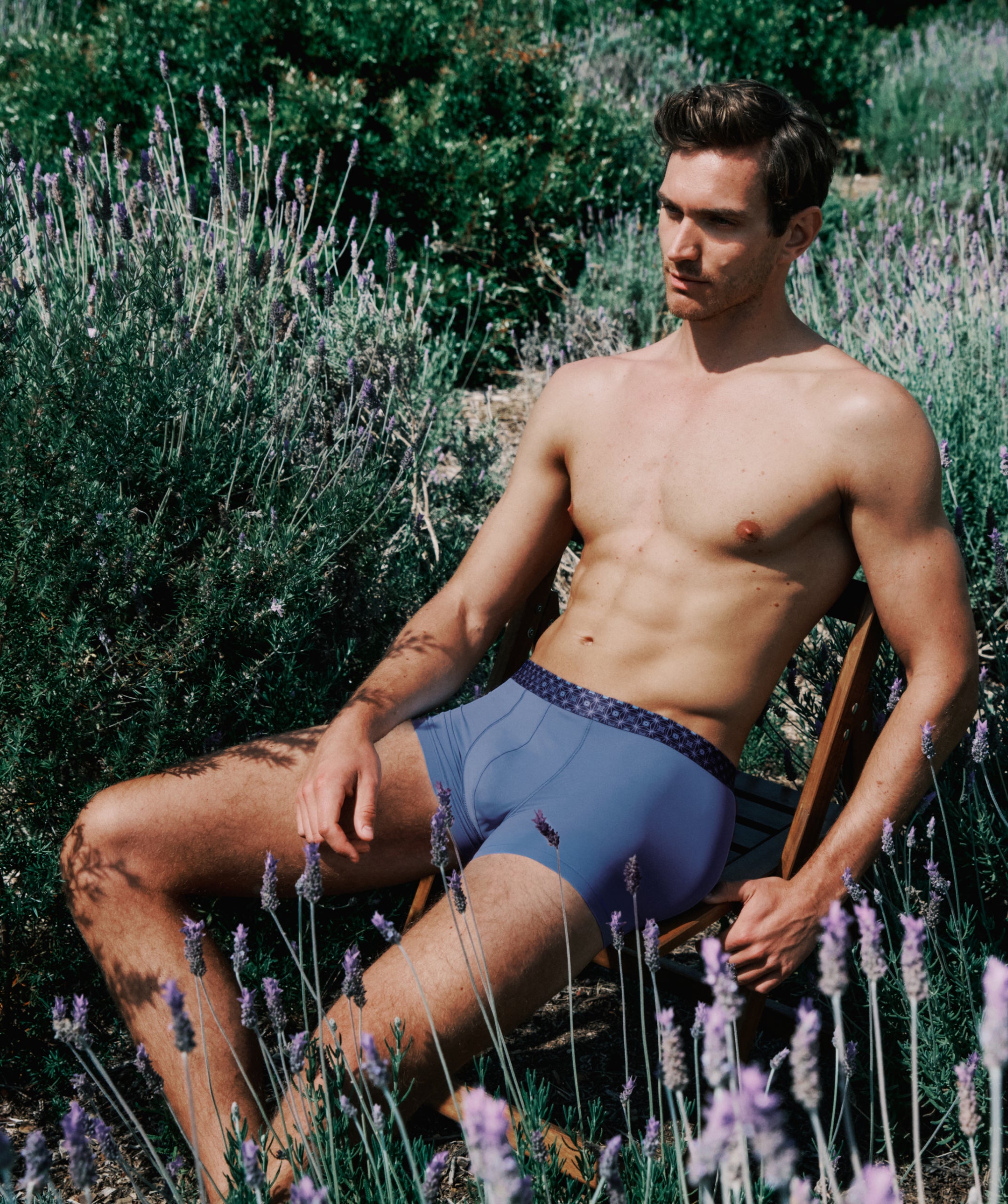 Man sitting among lavender plants wearing blue underwear.