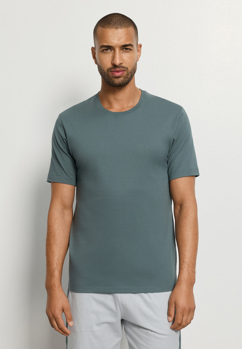 Man wearing a plain green t-shirt against a light gray background