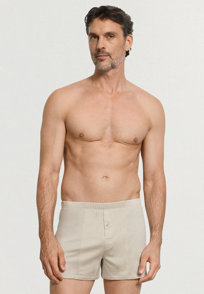 Man wearing beige boxer shorts against a plain background