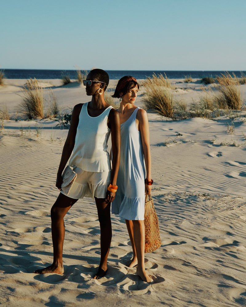 Two people standing on a sandy beach with ocean in the background