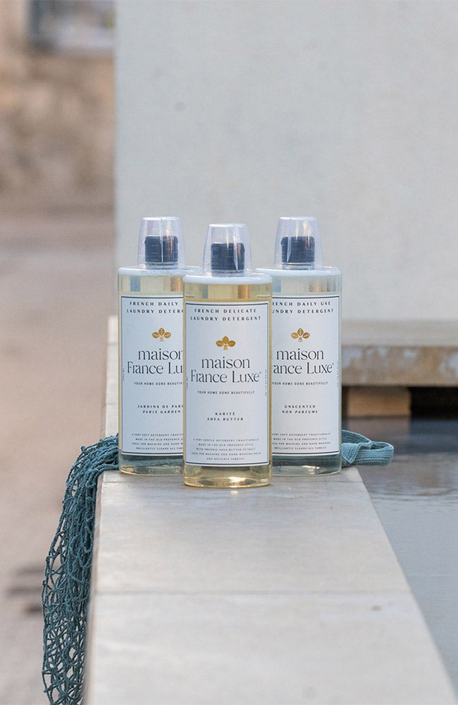 Three bottles of Maison France Luxe on a stone surface with a blurred background