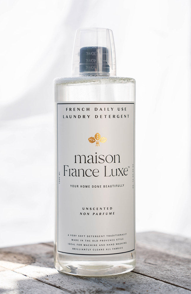 Bottle of maison France Luxe laundry detergent on a wooden surface with a white background