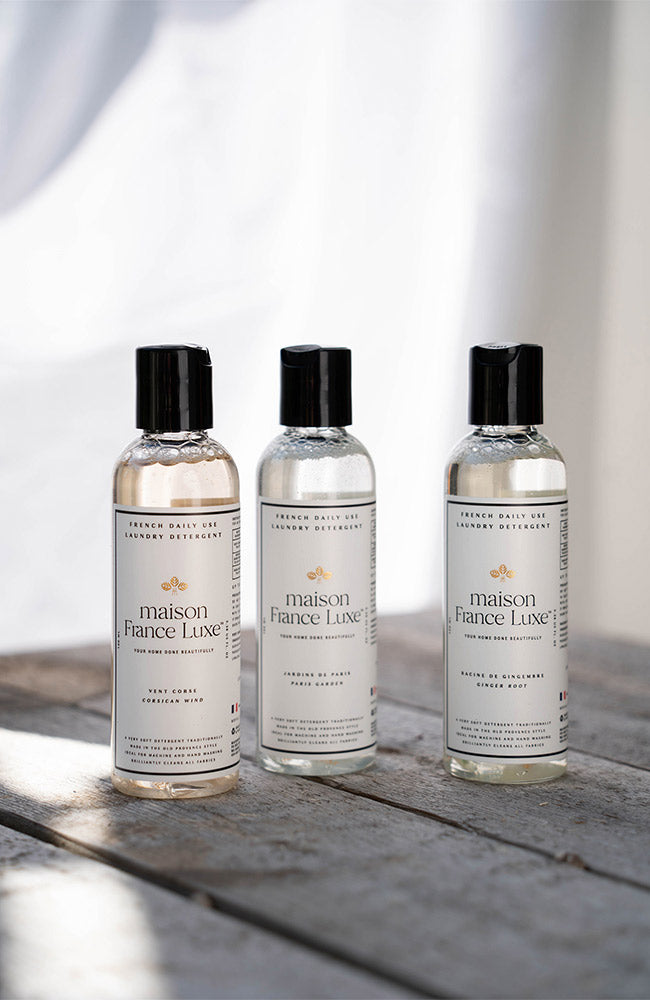Three bottles of maison France Luxe products on a wooden surface with a blurred background