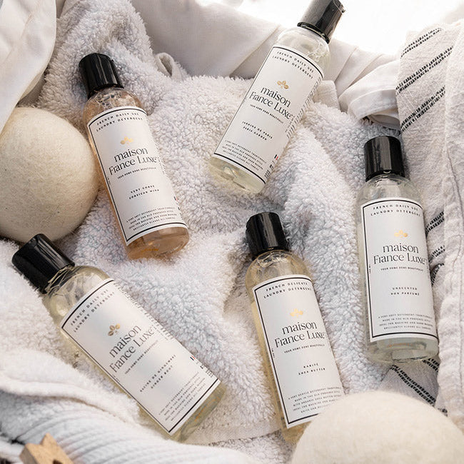 Five bottles of maison Fiance Luxe products on a textured white surface.